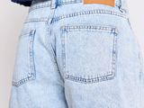 the back view of a woman wearing a blue top and denim shorts