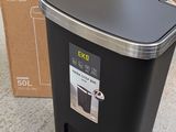 a black trash can sitting on the floor next to a cardboard box
