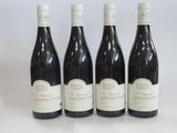 four bottles of red wine are lined up on a white surface