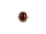 a close up of a gold ring with a red stone