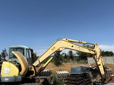 une pelleteuse jaune qui est à l'arrêt dans la terre