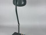 a green desk lamp with a cord plugged to it ' s base