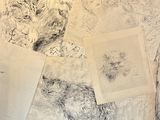 a pile of drawings on a table next to a laptop