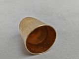 a close up of a gold thimble on a white surface