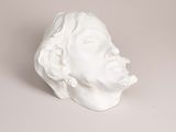 a white sculpture of a man ' s head on a table