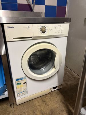 an image of a washing machine sitting in a kitchen next to a refrigerator