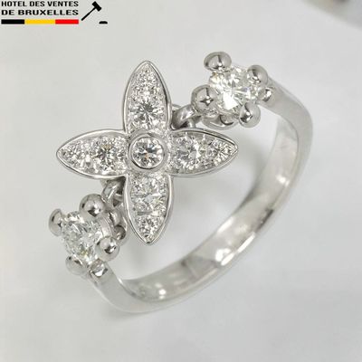 une image d'une bague ornée d'une fleur en diamant sur fond blanc