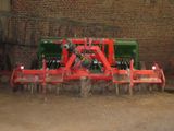 a tractor that is sitting in the dirt near a brick wall
