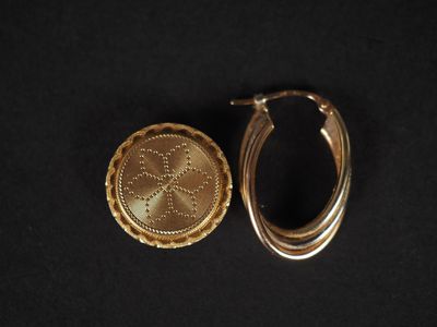 un gros plan sur une paire de boucles d'oreilles en or posées sur une surface noire