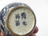 someone is holding a blue and white vase with chinese writing on it
