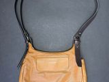 une image représentant un sac à main marron posé sur une surface noire