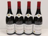 quatre bouteilles de vin rouge sont alignées sur une table