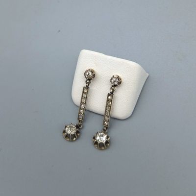 une paire de boucles d'oreilles en diamant posées sur un tissu blanc