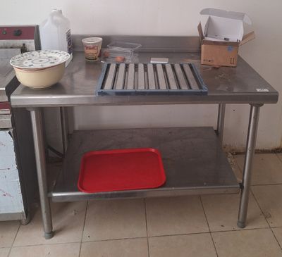 une cuisine avec une table en inox et un plateau rouge