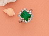 gros plan d'une bague avec une pierre verte entourée de diamants