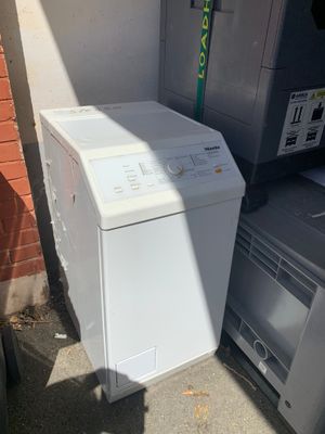 une machine à laver blanche posée à côté d'une pile d'autres appareils électroménagers