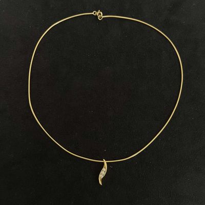 a gold necklace with a leaf charm on a black background