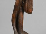 a close up of a wooden sculpture of a person with a bowl on his head