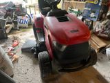 a man that is standing on a lawn mower in a garage