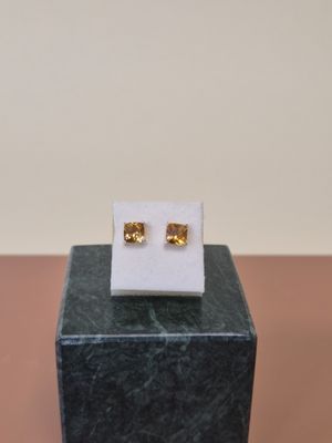 une paire de boucles d'oreilles en or posée sur un bloc de marbre
