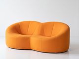 an orange couch sitting on top of a white floor next to a white wall