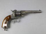 un vieux revolver avec une poignée en bois sur une surface blanche