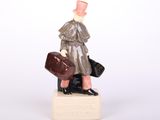 une figurine d'un homme avec une valise sur un piédestal