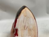 a hand holding a ceramic object with a red and black design on it