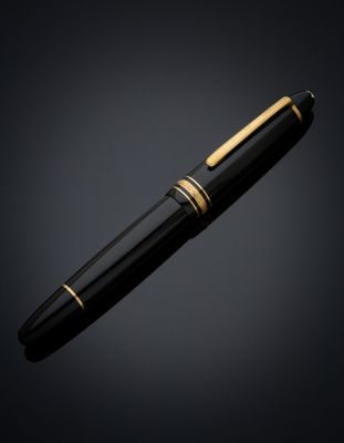 a black and gold pen with a gold tip on a dark background