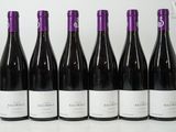 six bouteilles de vin sont alignées sur une table