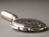 a silver pocket watch with a coin on it