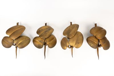 quatre figurines en laiton de tailles et de formes différentes posées sur une surface blanche