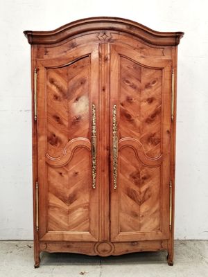 une armoire ancienne en bois, dont les portes sont ornées de ferrures en laiton