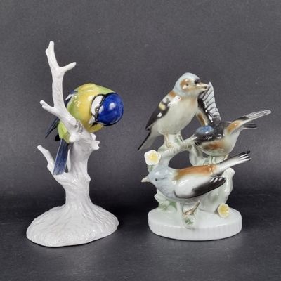 two figurines of birds sitting on a tree branch