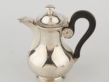 a silver coffee pot with a black handle on a white surface