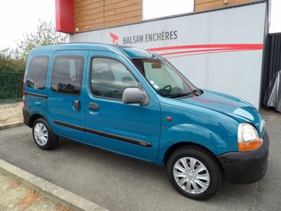 La petite camionnette bleue est garée devant un immeuble.