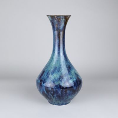 un vase bleu posé sur une table près d'un mur blanc
