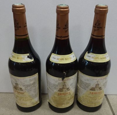 three bottles of wine are lined up on a tile floor