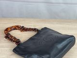 black leather handbag with tortoises and chain strap