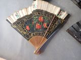 a black and gold fan with red flowers on it