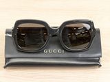 gucci sunglasses on a black case on a wooden table