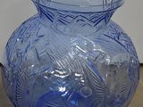 un vase en verre bleu posé sur un mur, à côté d'un mur blanc