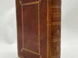 an old book with a brown cover sitting on top of a white surface