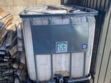 un grand conteneur métallique sur lequel est collé un autocollant, à côté d'un tas de bois