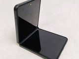 the back of a black cell phone sitting on top of a white surface