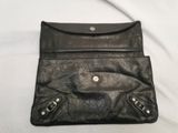 black leather purse with two zippers on it on a white surface