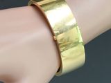 the hand is holding a gold bracelet on it ' s wrist