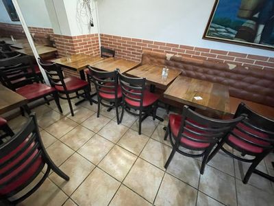tables and chairs are lined up in a restaurant with a brick wall