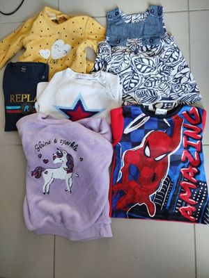 plusieurs vêtements d'enfants étalés sur un sol carrelé