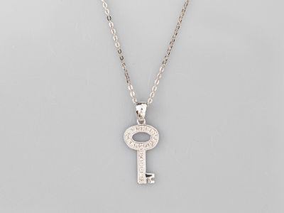 un collier composé d'une clé en argent suspendue à une chaîne, à laquelle est attachée une autre chaîne